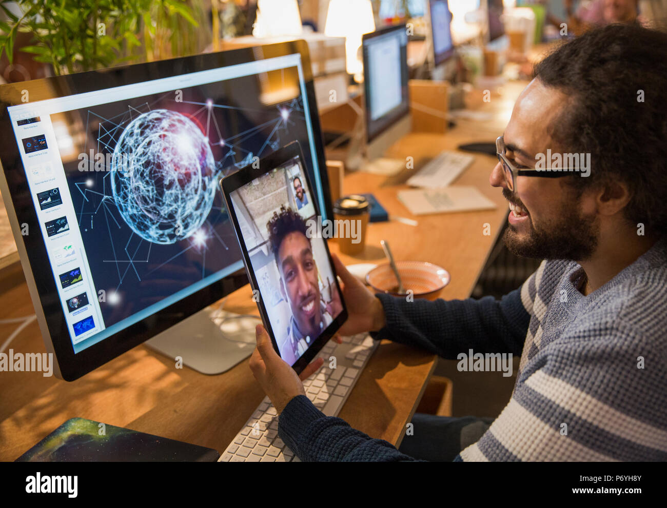 Diseñador gráfico videochats con su colega sobre la tableta digital en Office Foto de stock