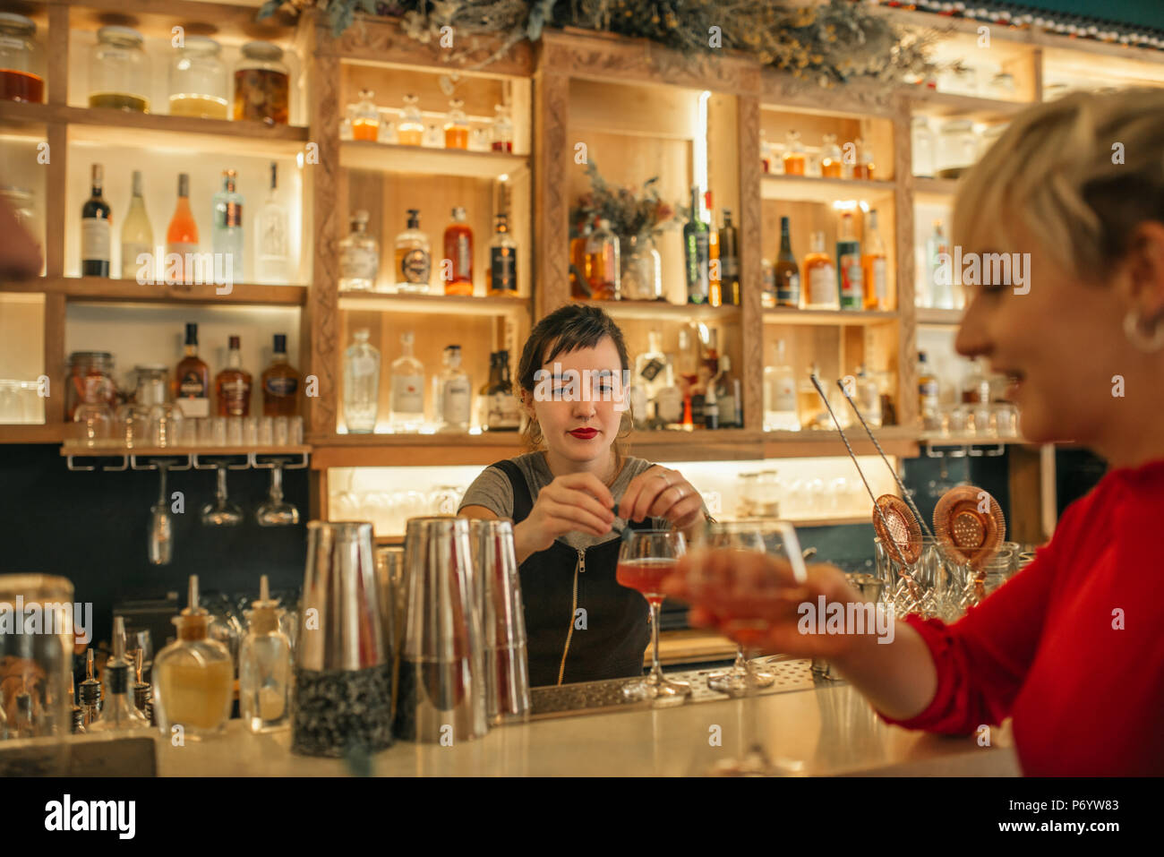 Las hembras jóvenes barman haciendo cócteles detrás de un mostrador de bar Foto de stock