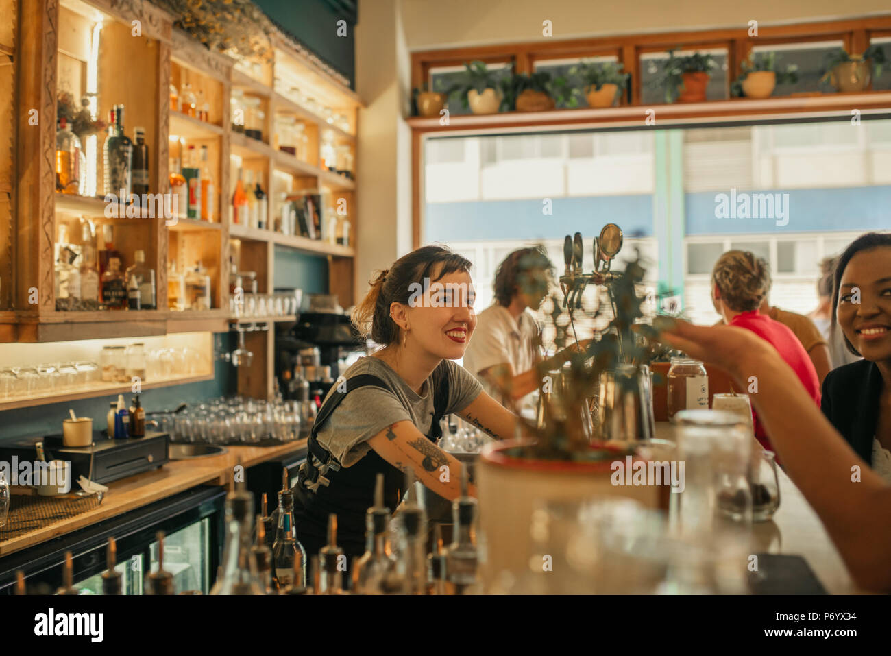 Mujer sonriente camarero, hablar con los clientes en un mostrador de bar Foto de stock