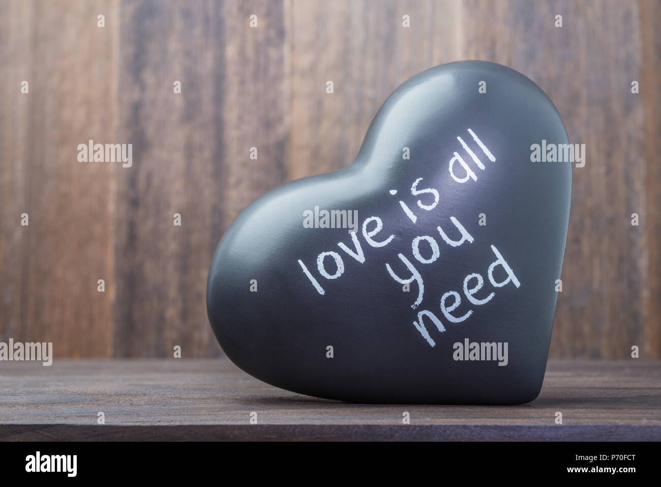 Corazón negro de cerámica sobre fondo de madera con mensaje como símbolo de día de San Valentín Foto de stock
