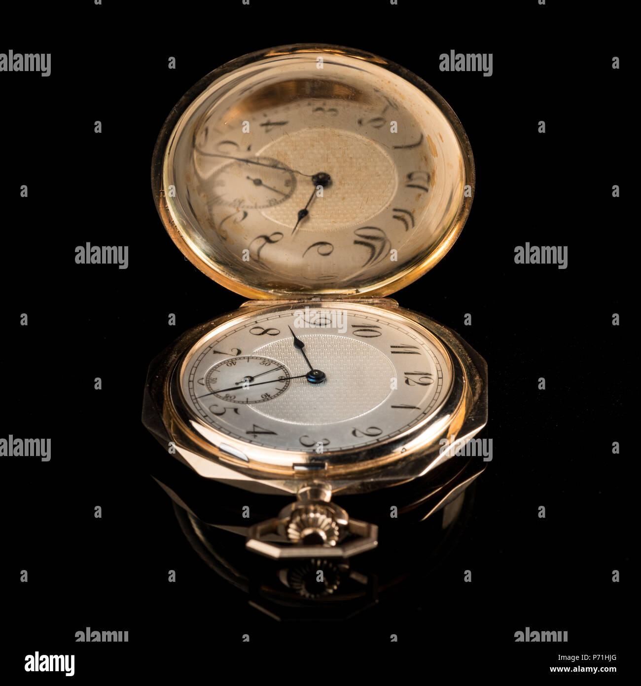 Primer plano de un antiguo reloj de bolsillo de oro, usado con abrir la tapa  sobre una superficie reflectante negro Fotografía de stock - Alamy