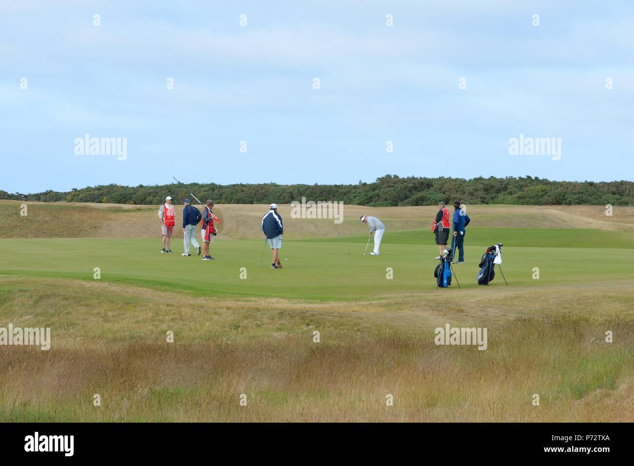 Los golfistas y caddies el 18 verde en el Royal Dornoch Golf Club, Sutherland, Scotland, Reino Unido Foto de stock