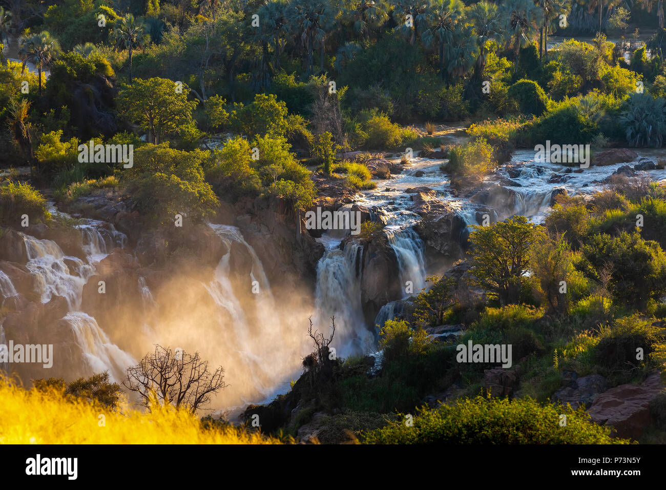 Epupa Falls en el río Kunene, en el norte de Namibia y sur de Angola frontera. Amanecer la luz solar en el agua nebulizada. Foto de stock