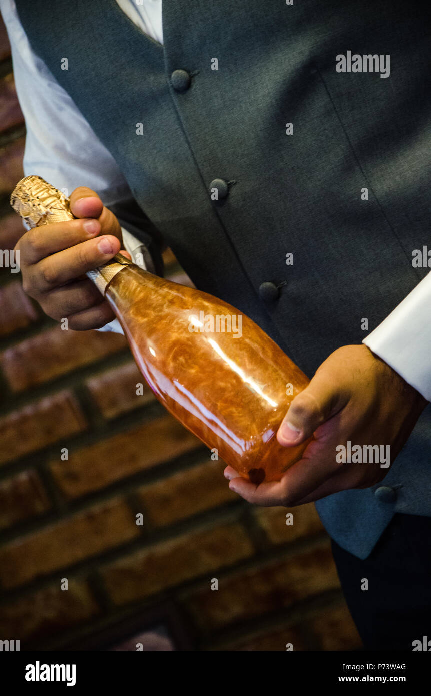 Hombre elegante novio sosteniendo una botella de champaña dorado. recepción de bodas de lujo. servicio de catering y servicio de restaurante en el espacio para el texto. Foto de stock