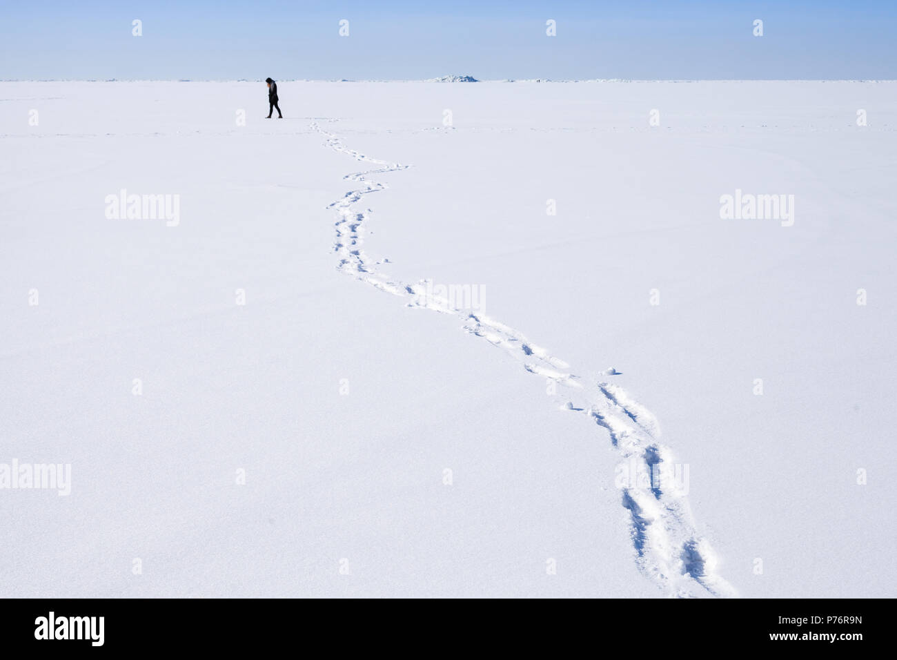Huellas de lonely persona caminando a lo largo de la interminable campo de nieve Foto de stock