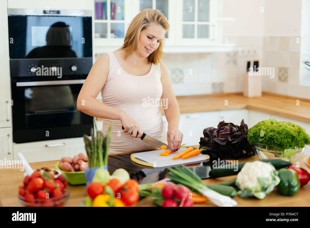 Mujer embarazada hacer una comida en la cocina Foto de stock