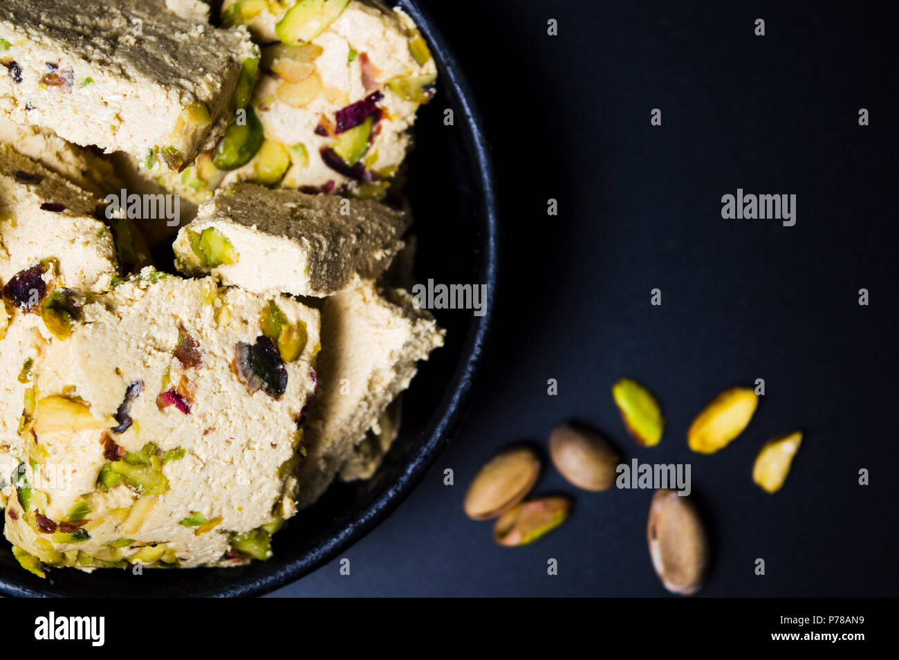 Postre Halva con pistachos en una placa oscura Foto de stock
