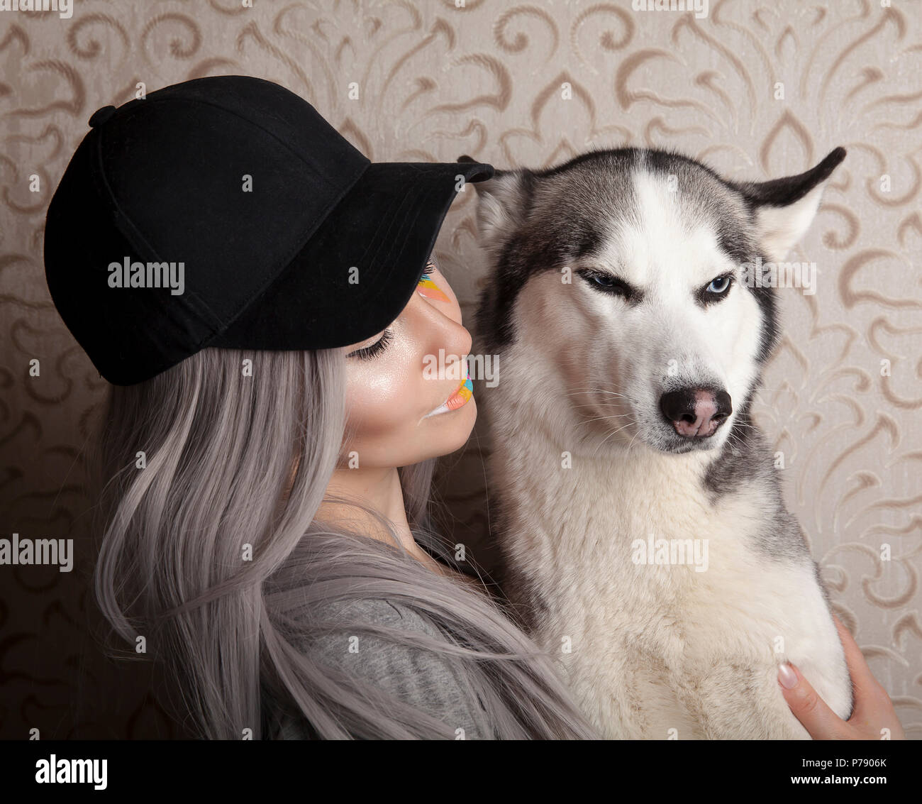 Estudio de la imagen de una mujer joven, sosteniendo su perro husky, en un segundo plano. Foto de stock