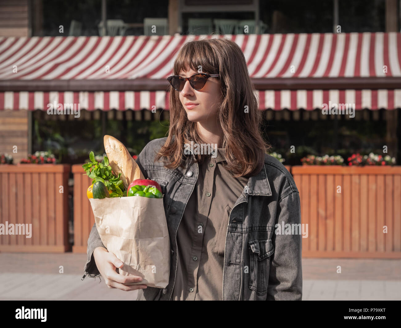 Atractiva mujer joven en estilo casual Ropa celebración comestibles  comprados de verduras locales y tienda de abarrotes o mercado. Bolsa de  papel reciclable hea Fotografía de stock - Alamy