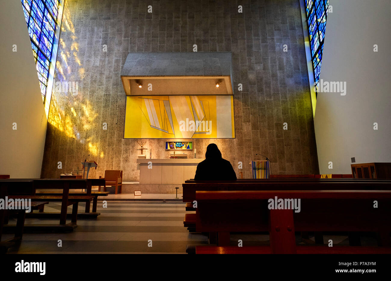 Mujer orando con la cabeza cubierta en una de las capillas laterales de Liverpool Catedral Metropolitana de Cristo Rey Foto de stock