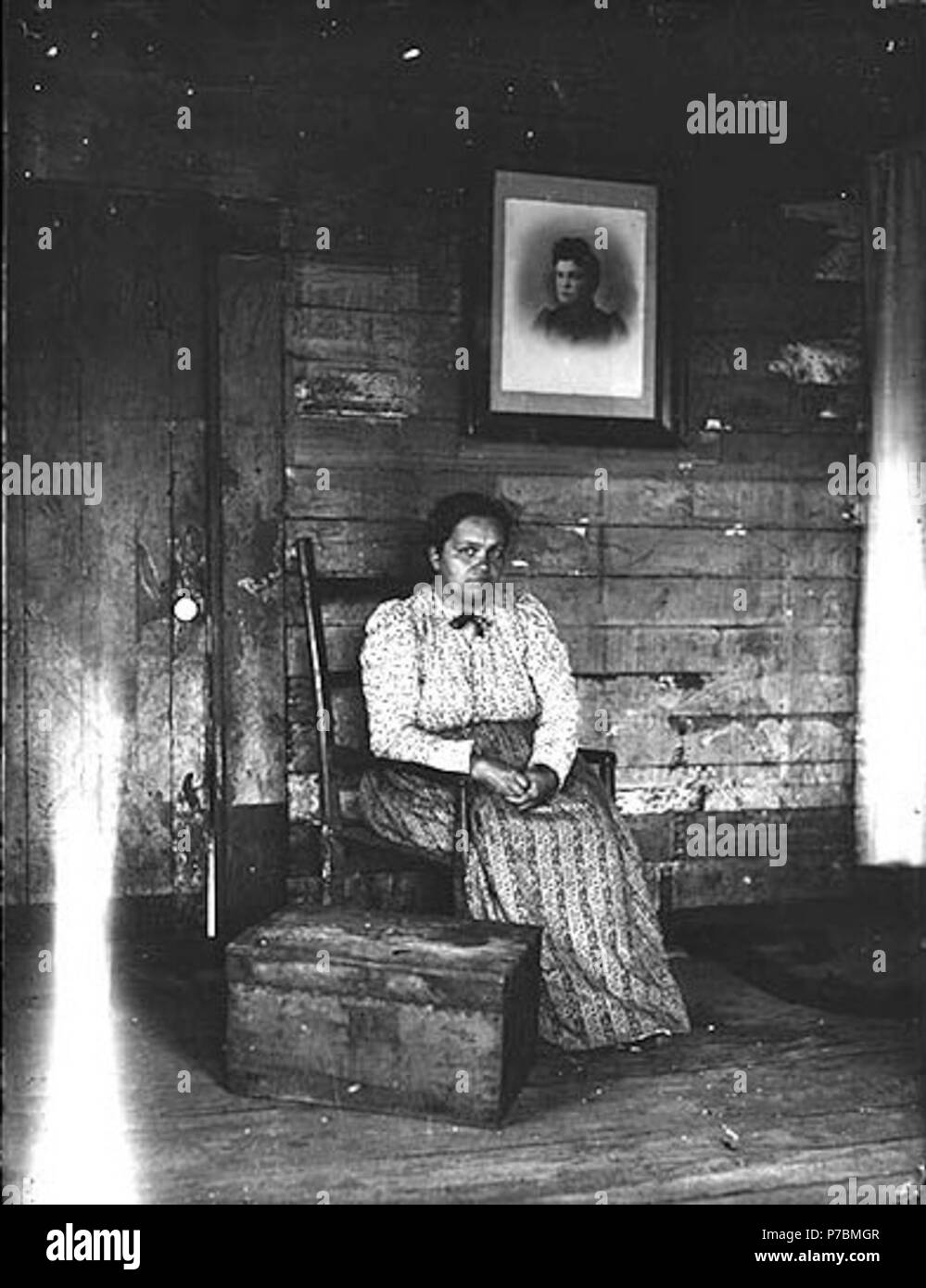 Inglés: mujer no identificada sentado en una silla, Washington, ca. 1905 .  Inglés: Interior de la habitación. Mujer sentada en la silla junto al  pecho. Enmarcado retrato de mujer en la