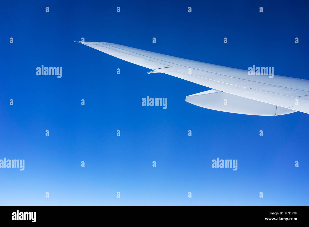 Ala de avión blanco graduado aislado en un cielo azul. Concepto de vuelo y viajes. Foto de stock