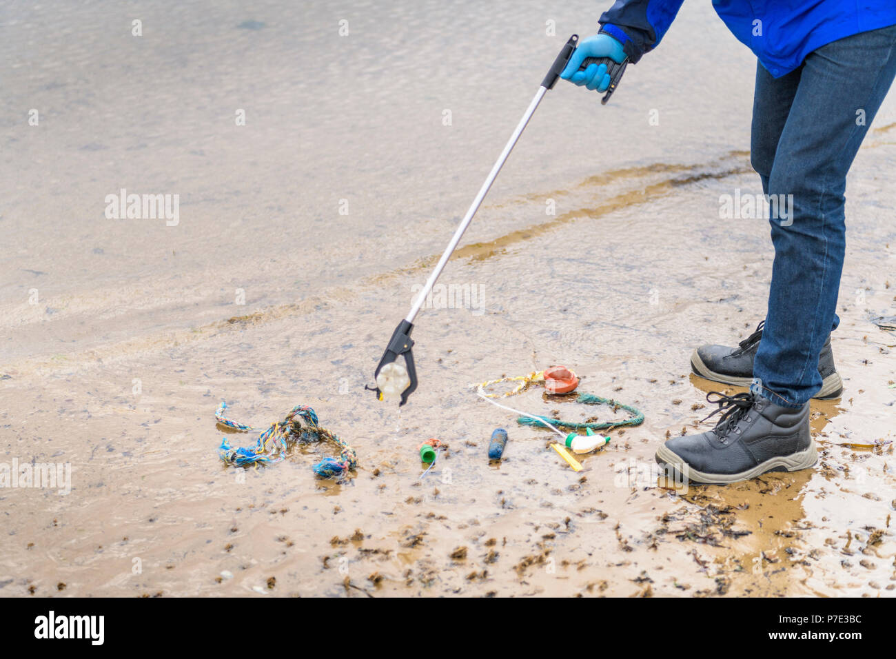 Hombre utilizando el selector de basura para eliminar la contaminación de plástico recogidos en la playa, al Noreste de Inglaterra, Reino Unido. Foto de stock