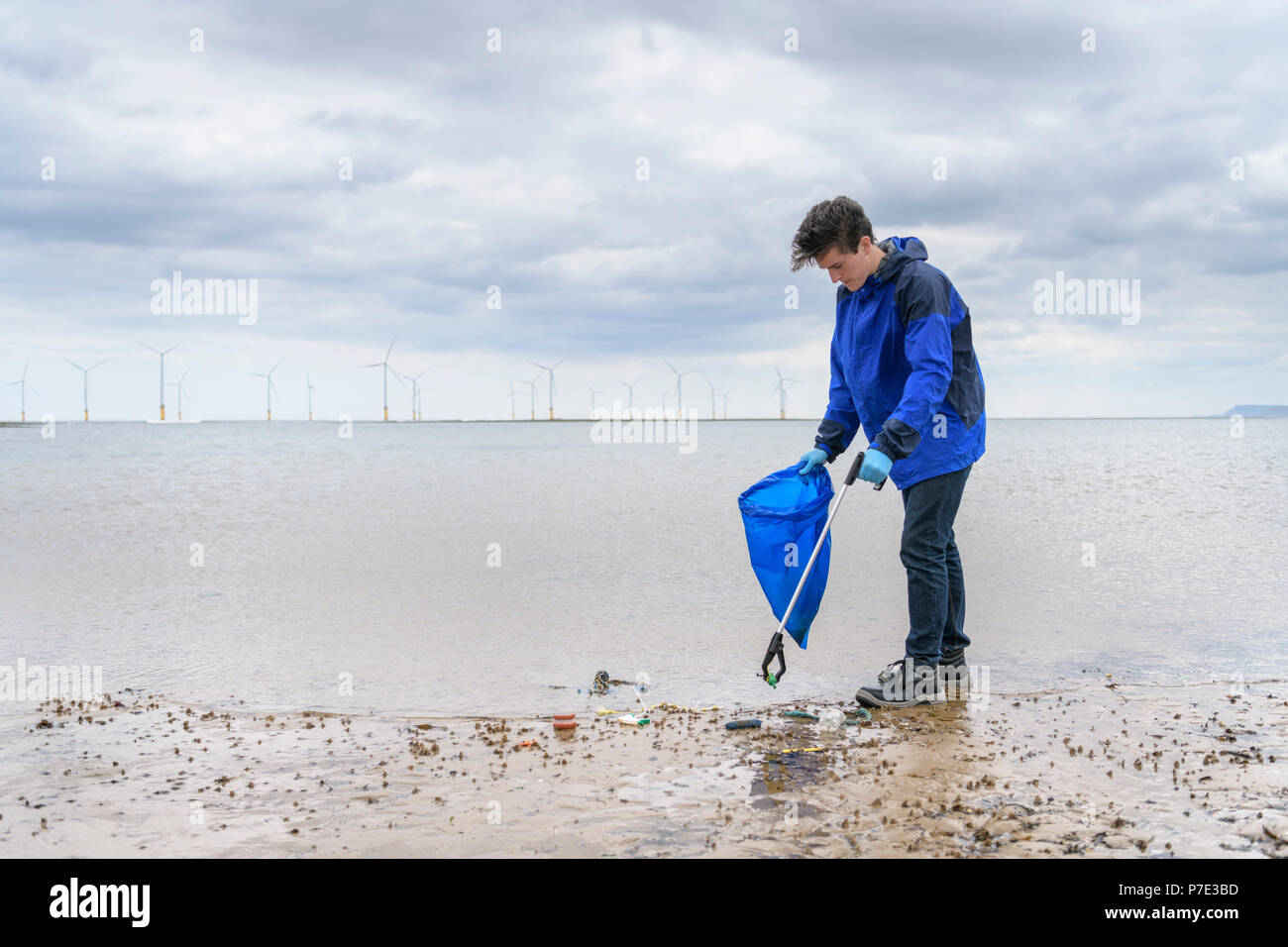 Hombre utilizando el selector de basura para eliminar la contaminación de plástico recogidos en la playa, al Noreste de Inglaterra, Reino Unido. Foto de stock