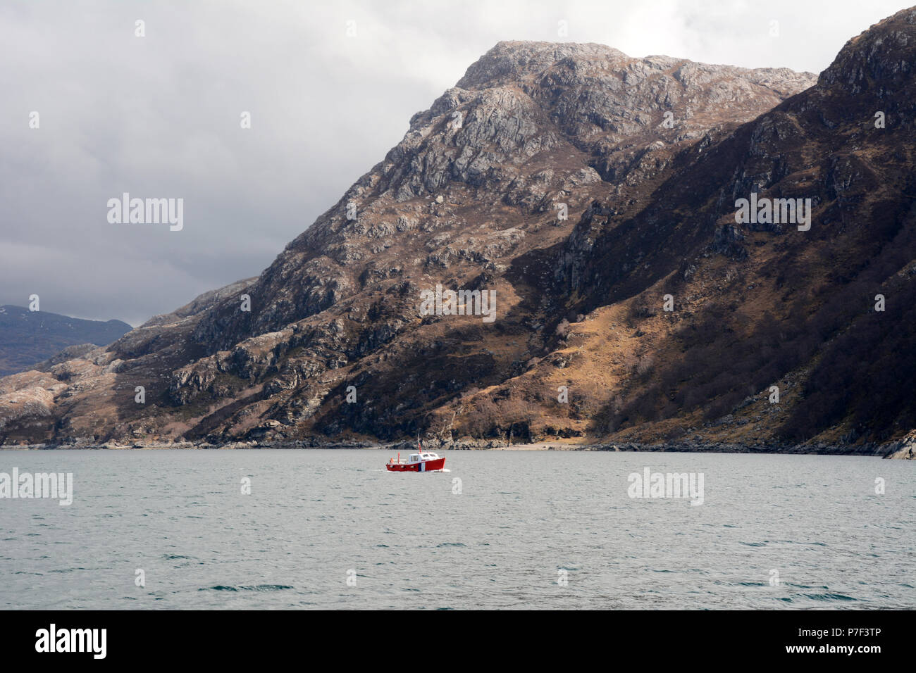 Un barco bajo las montañas en Loch Nevis frente a las costas de la península Knoydart, al noroeste de Las Tierras Altas de Escocia, Escocia, Gran Bretaña. Foto de stock