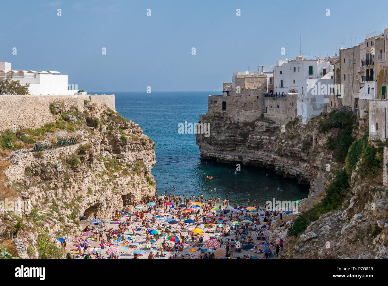 Polignano a Mare, Italia - Personas bañarse en el Mar Mediterráneo en la playa de la ciudad Polignano a Mare, ciudad con playa en Apulia, en el sur de Italia. Foto de stock