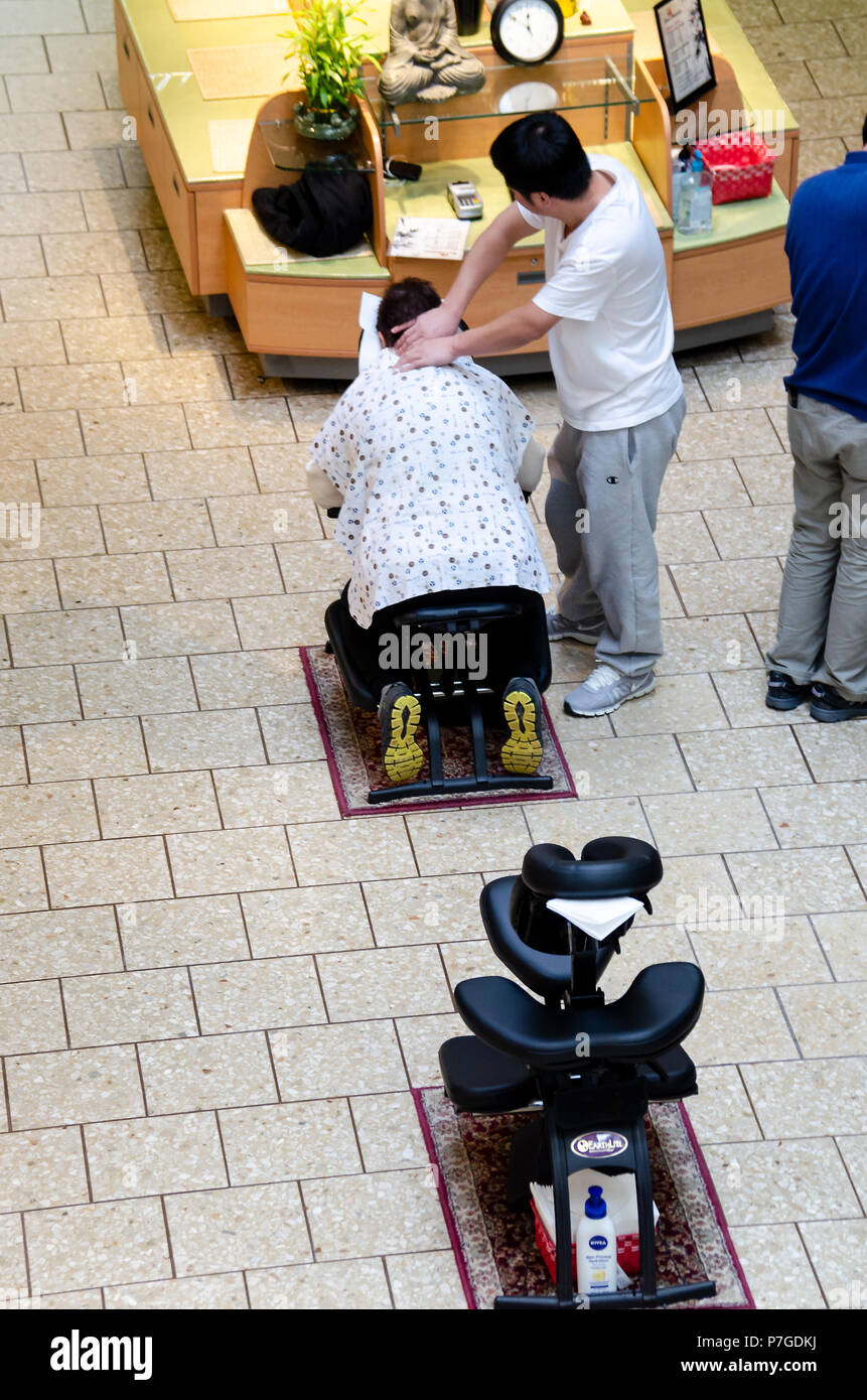 Fairfax, ESTADOS UNIDOS - 2 de enero de 2015: Masajista haciendo sentado  masaje en el cuello para la mujer de más edad en Fair Oaks Mall, Virginia  Fotografía de stock - Alamy