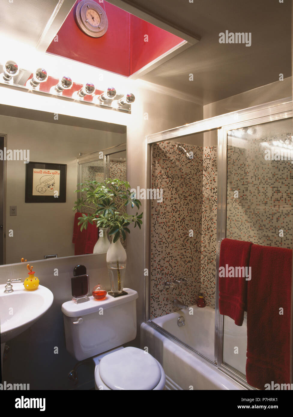 Rosa claraboya encima de espejo en la pared del cuarto de baño pequeño gris  con mampara de cristal en el baño Fotografía de stock - Alamy