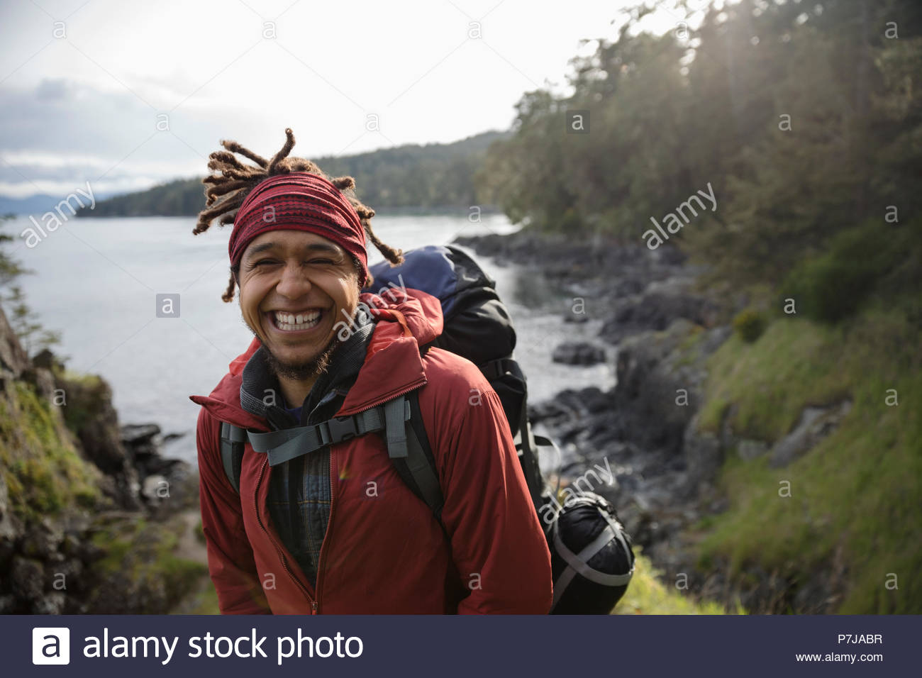 Retrato feliz, entusiasta mochilero macho de senderismo a lo largo de ocean Foto de stock