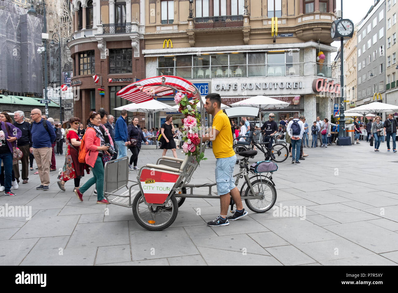 Un paraguas de bicicletas cubierto taxi y su operador en Stock Im Eisen platz en Viena, Auastria. Foto de stock