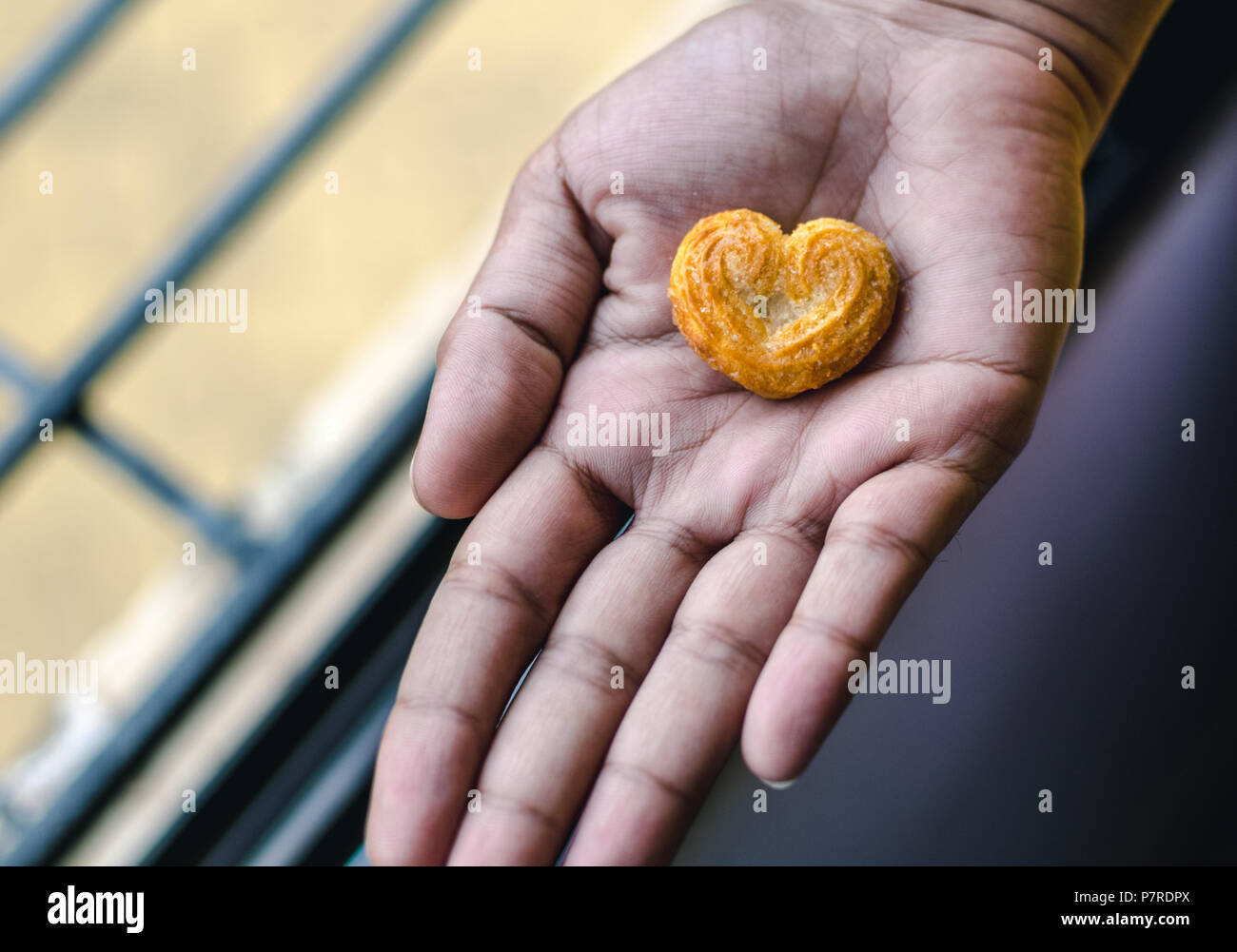 Una chica sujetando una galleta en forma de corazón en su palm Foto de stock