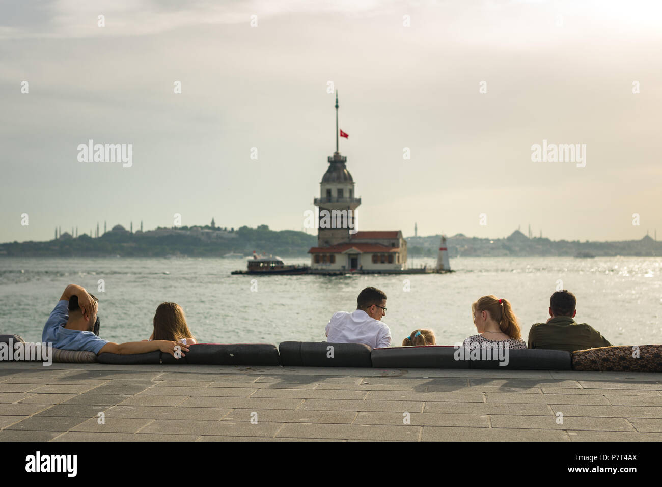 Personas sentadas disfrutando de la vista con la Torre de la Doncella o Kız Kulesi en el fondo, Estambul, Turquía Foto de stock