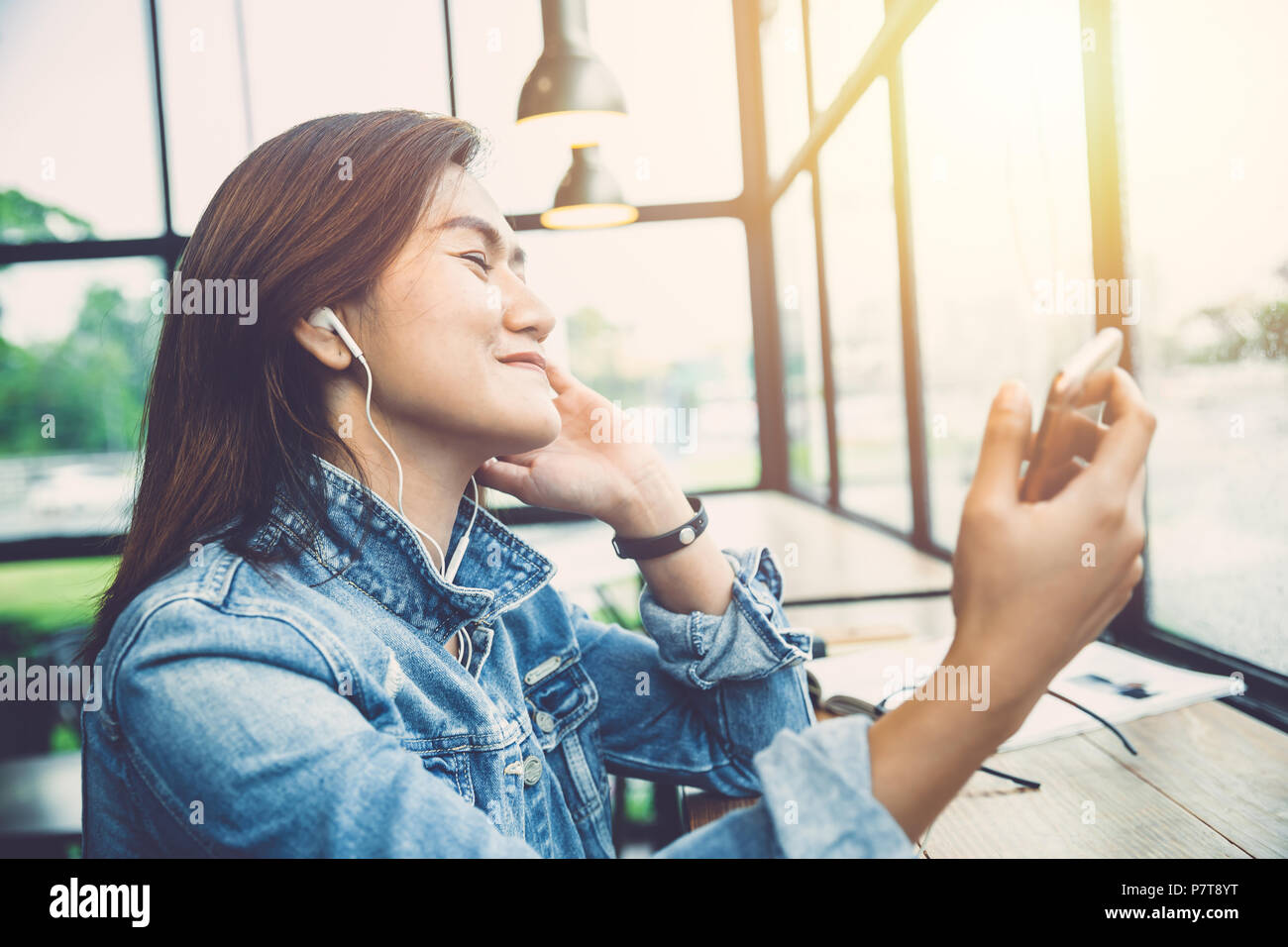 Hipster mujer disfrutar escuchando música desde el teléfono de APP en el café relax vacacional Foto de stock