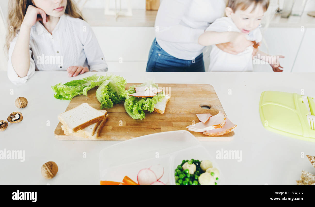 Madre preparar merienda escolar o almuerzo para niños en la cocina de casa por la mañana Foto de stock