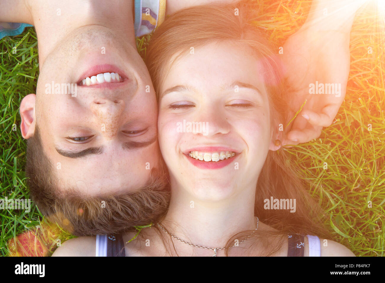 Joven pareja feliz tumbado en una pradera en el sol Foto de stock