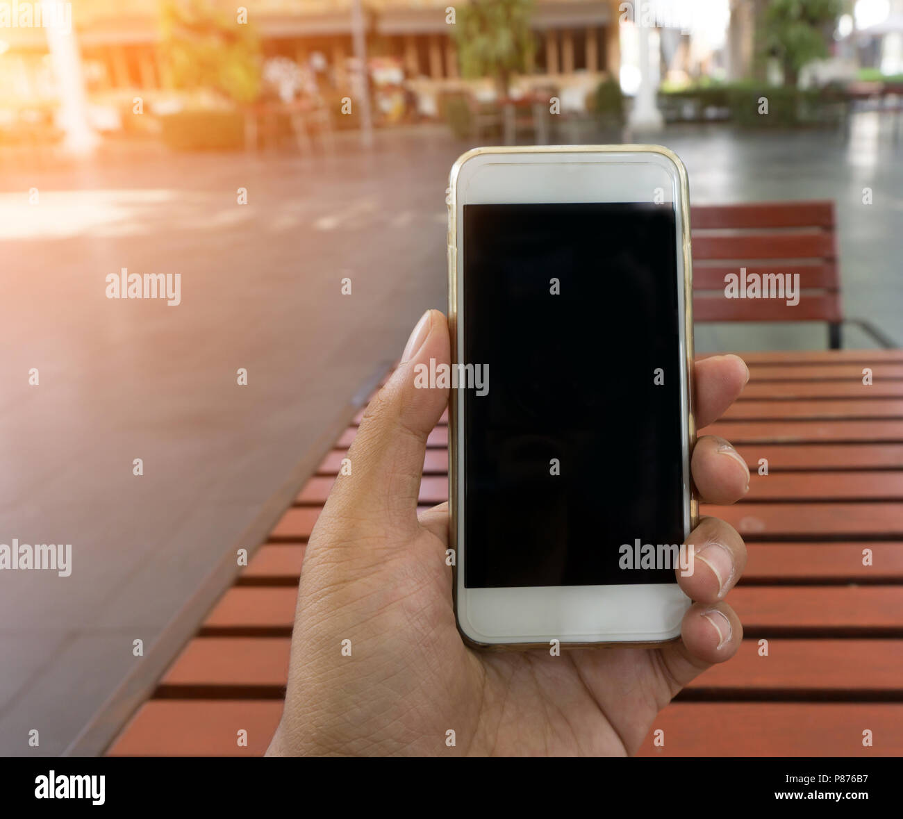 La mano del hombre muestra smartphone móvil en posición vertical, Boceto plantilla con fondo borroso - Sunset efecto de filtro Foto de stock