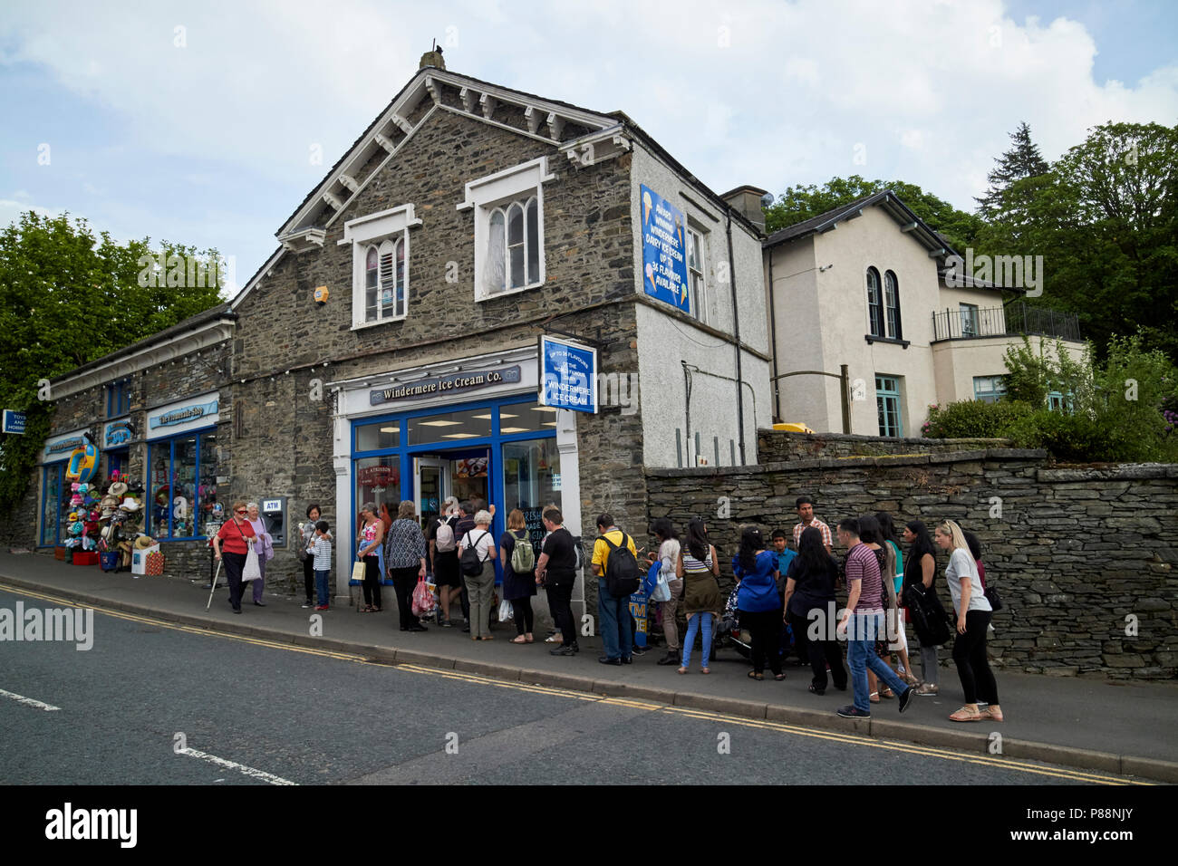 Larga cola de gente fuera de Windermere helado co shop en Bowness On Windermere Cumbria, Lake District, Inglaterra Foto de stock
