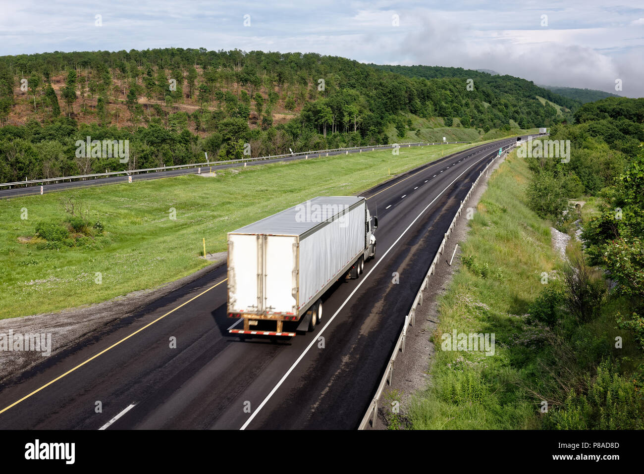 Camiones que circulaban por la carretera interestatal a través de pintorescas montañas orientales, tráileres en la industria de camiones transportando mercancías, el desenfoque. Foto de stock