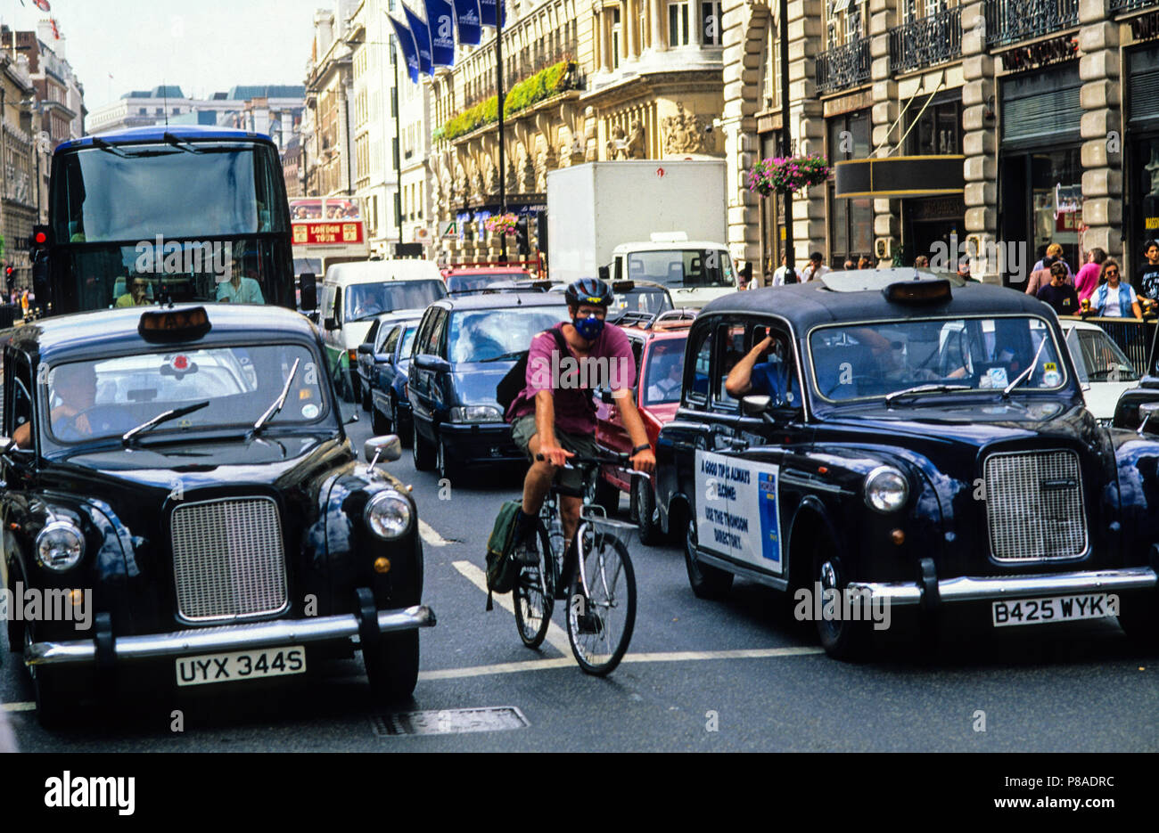 Ciclista de la máscara facial, ciclismo en tráfico denso, London, UK, GB. Foto de stock