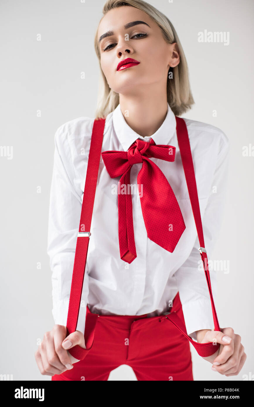 Chica de moda posando con la camisa blanca, tirantes y lazo rojo, aislado  sobre fondo gris Fotografía de stock - Alamy