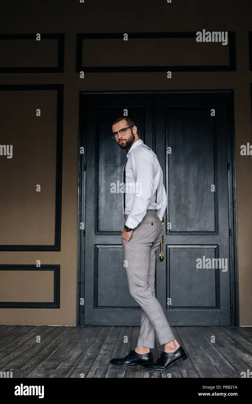 Moda hombre elegante posando con la camisa blanca y tirantes contra la  puerta en loft interior Fotografía de stock - Alamy
