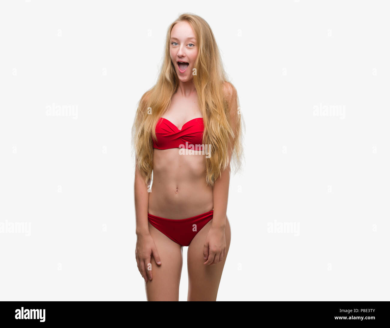 Adolescente rubia mujer vistiendo bikini rojo miedo y consternada con expresión de sorpresa, miedo y entusiasmado cara. Foto de stock