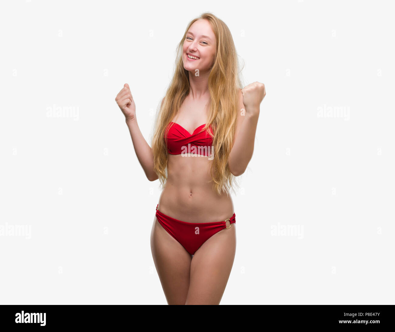 Adolescente rubia mujer vistiendo bikini rojo muy feliz y emocionado  ganador haciendo gestos con los brazos en alto, sonriendo y gritando por el  éxito. Celebración Fotografía de stock - Alamy