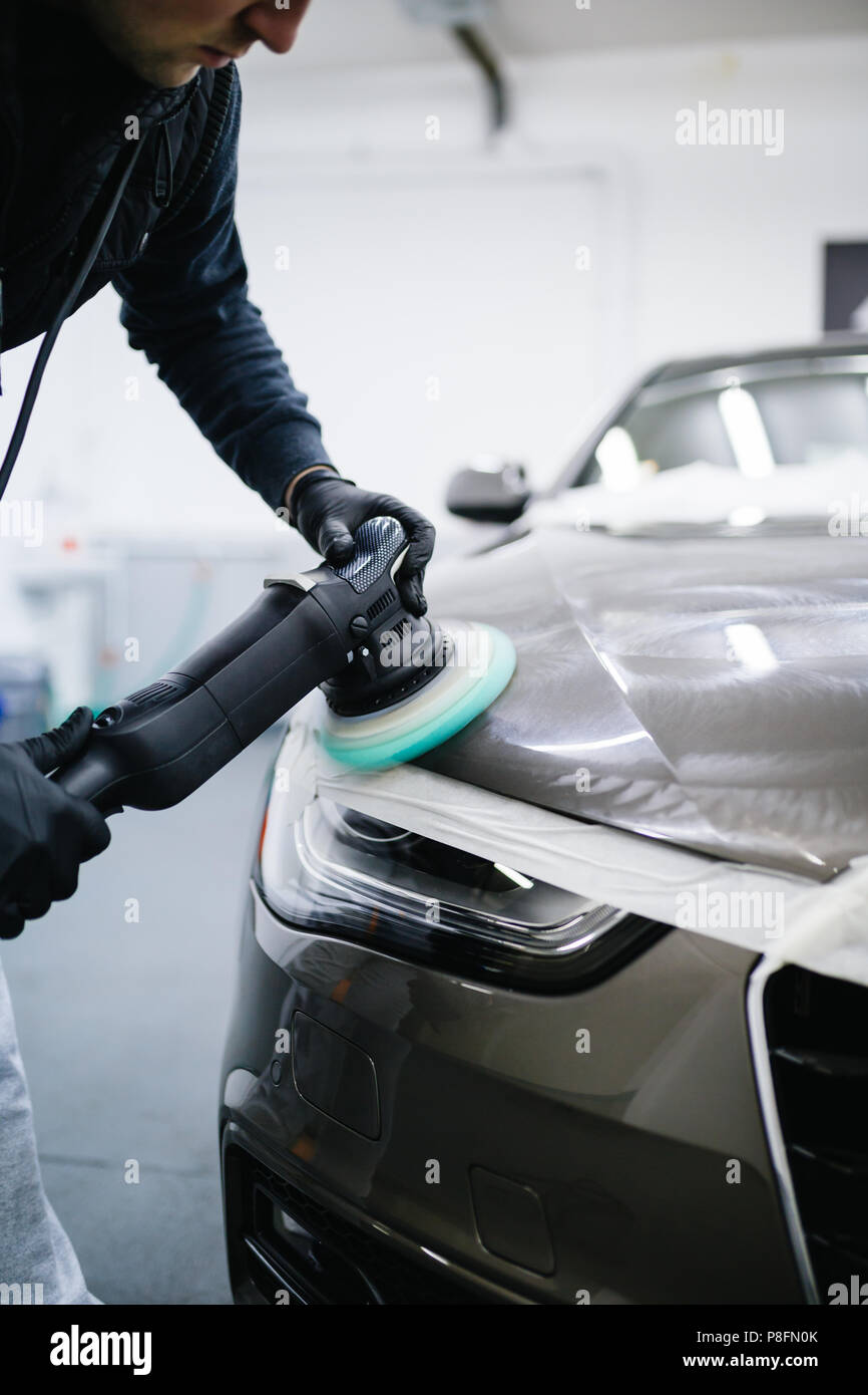 Coche detallando - Trabajador con pulidora orbital en taller de