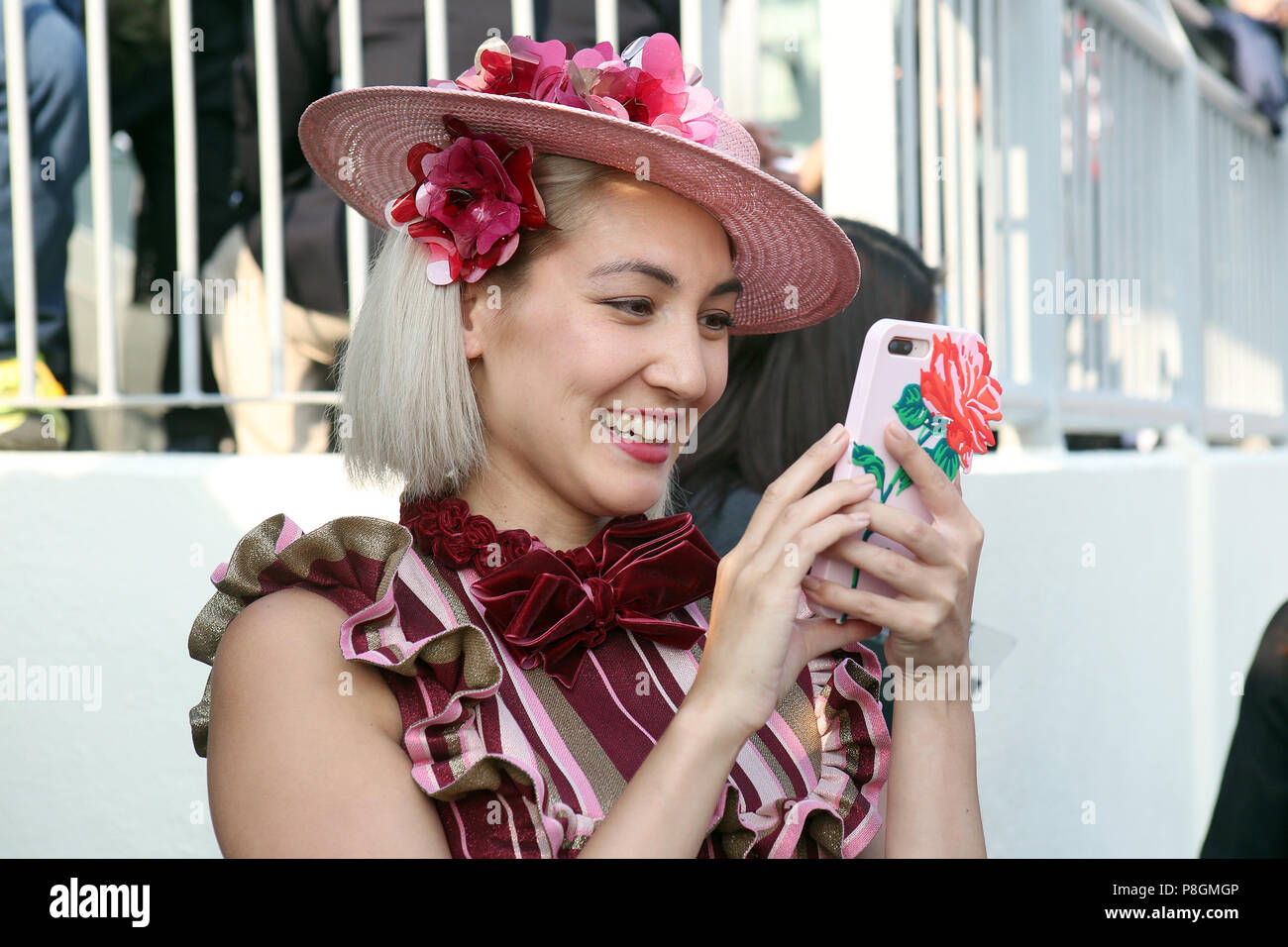 Hong Kong, China, elegantemente vestido mujer asiática con sombrero fotografiado con su smartphone Foto de stock