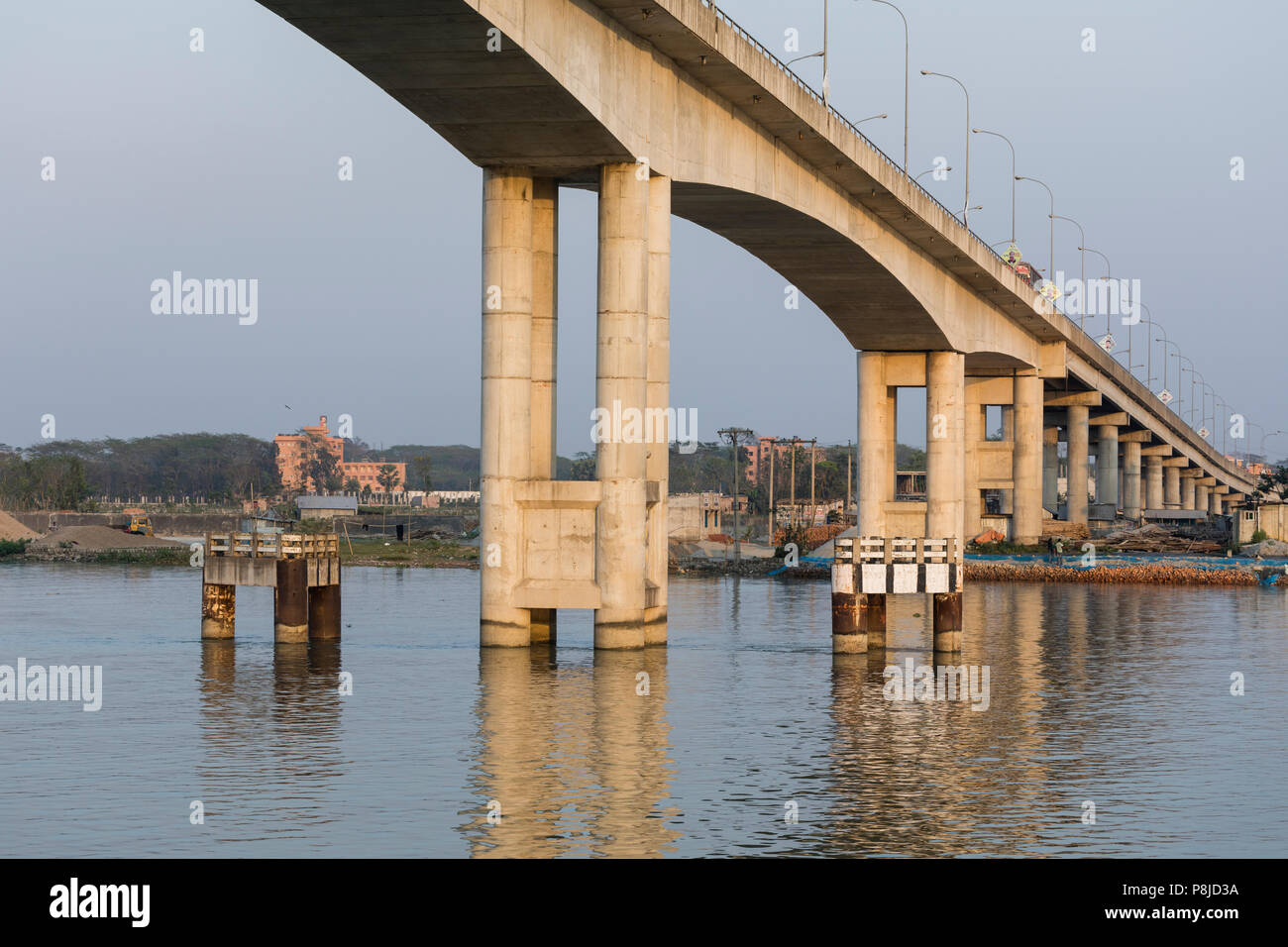 Khulna, Bangladesh, 1 de marzo de 2017: El moderno puente de hormigón en la luz de la tarde conduce a lo largo de un río en Bangladesh Foto de stock