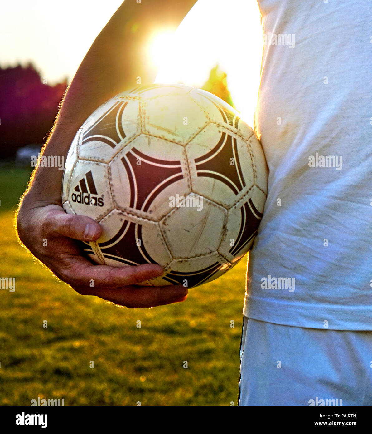 El futbolista mantiene su usado adidas tango ball en el campo Foto de stock