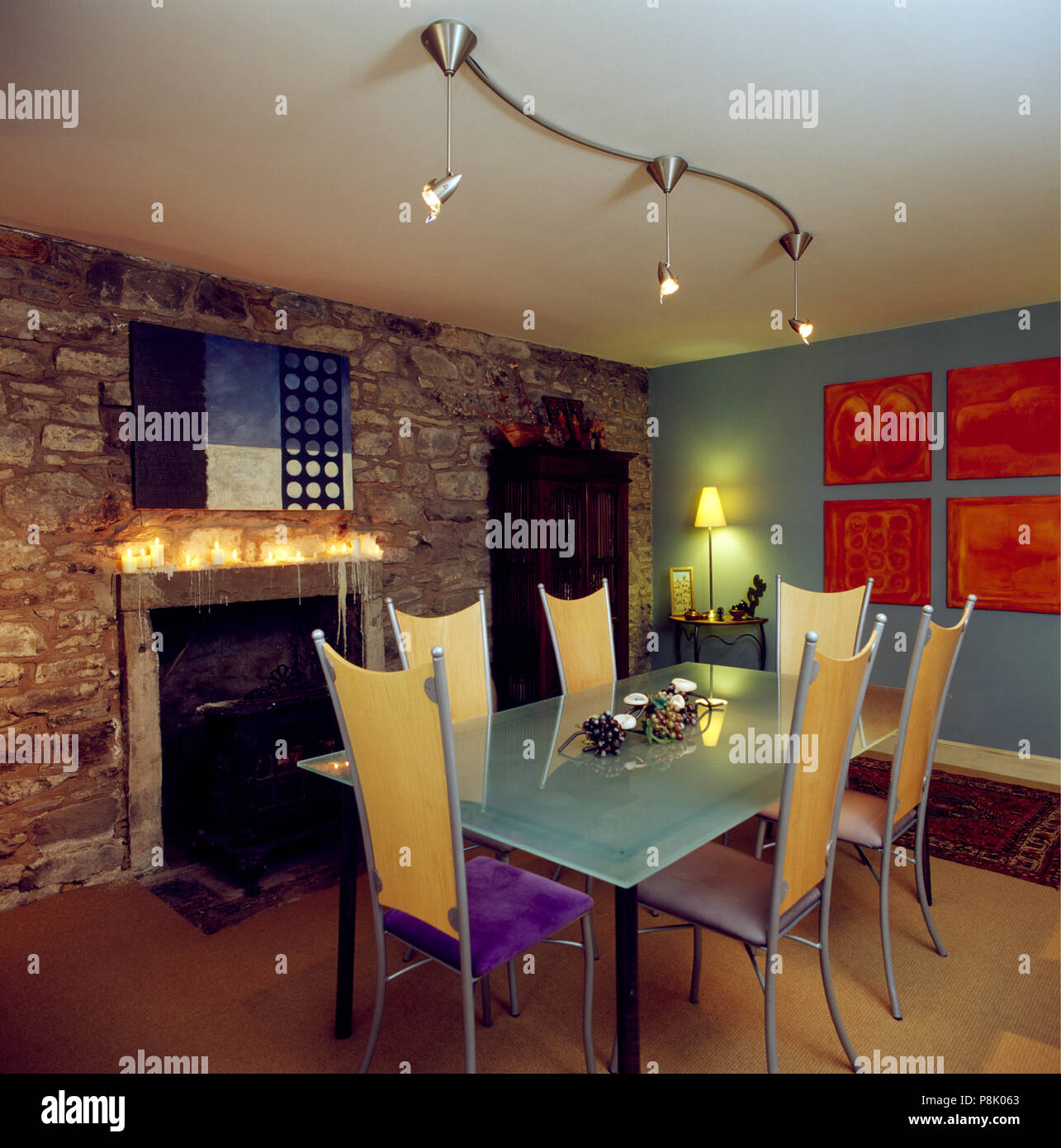 Tall-respaldado sillas y mesa rectangular debajo de focos halógenos en  salón-comedor con chimenea en la pared de piedra Fotografía de stock - Alamy