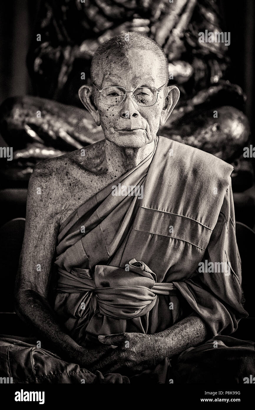 Un retrato de un varón anciano monje meditando en un templo en Tailandia. Foto de stock