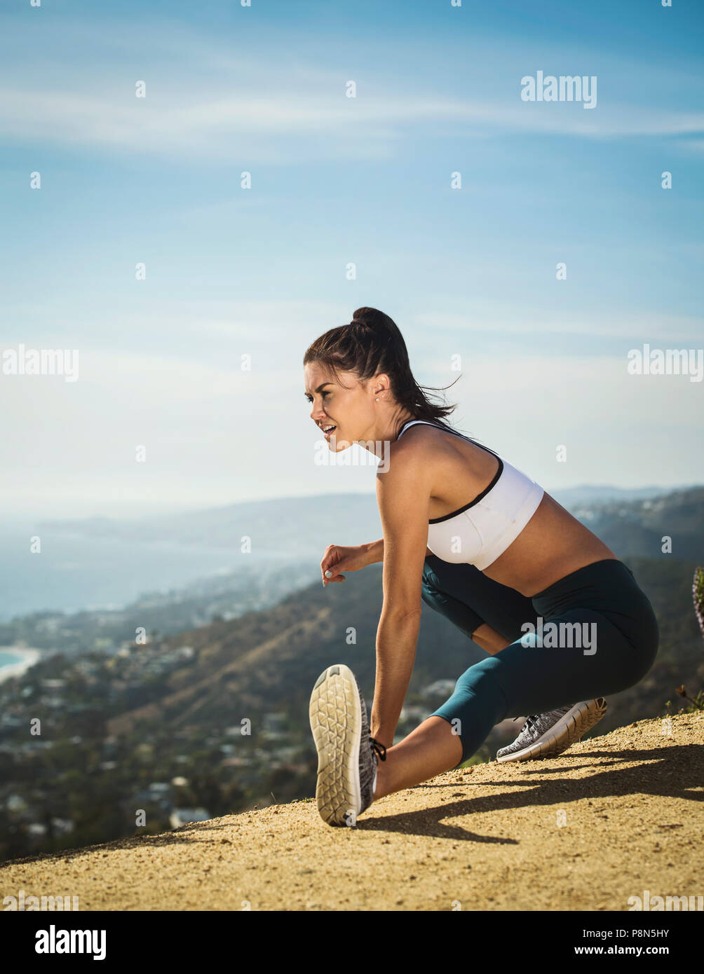 Mujer en sportswear estirándose en la montaña Foto de stock