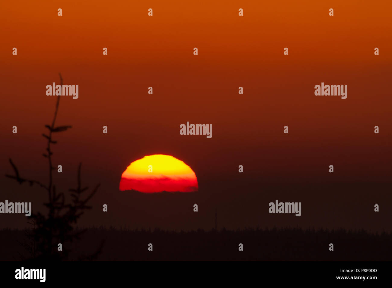 La puesta del sol parece ser aplanadas, como resultado de la flexión de los rayos de sol en este caso amplificado por la presencia de cenizas volcánicas en la atmósfera Foto de stock