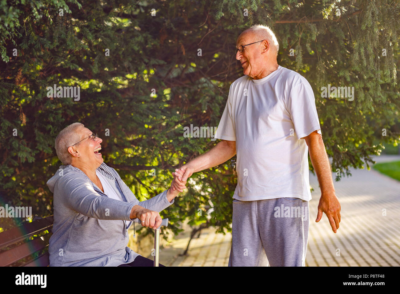 Los ancianos en park- viejo hombre sonriente esposa solícita en el parque Foto de stock