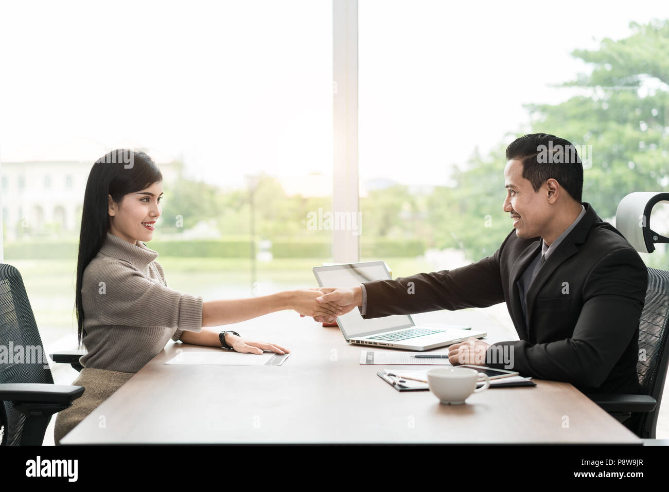 Par de empresarios asiáticos con ropa casual hablando con feliz y temblor de la mano en la oficina moderna o una cafetería. Concepto de éxito empresarial Foto de stock