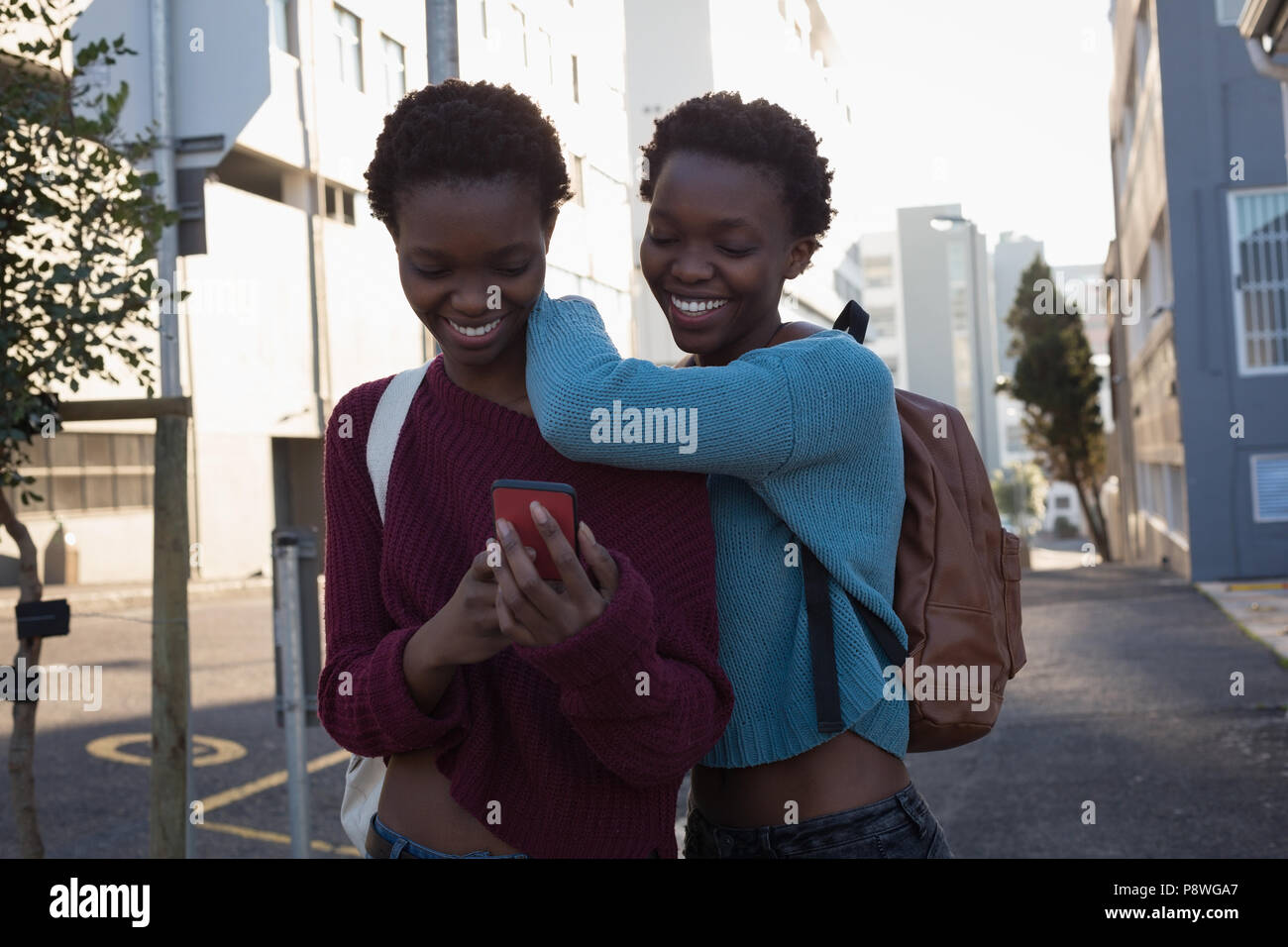 Hermanos gemelos a través de teléfono móvil en las calles de la ciudad Foto de stock