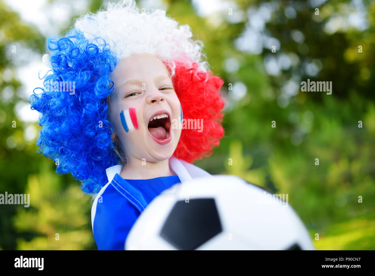 Funny Little Girl apoyando y animando a su equipo nacional de fútbol durante el campeonato de fútbol Foto de stock