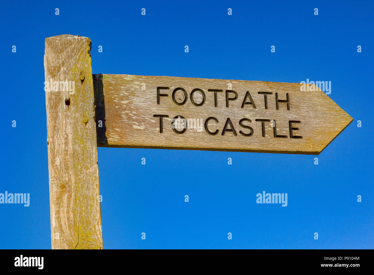 Cartel con el sendero al castillo escrito sobre ella, contra un cielo azul. Foto de stock